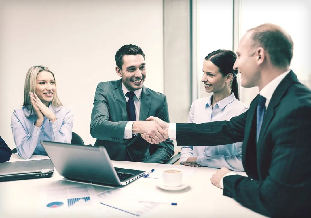 Two men in business suits shaking hands after making a deal